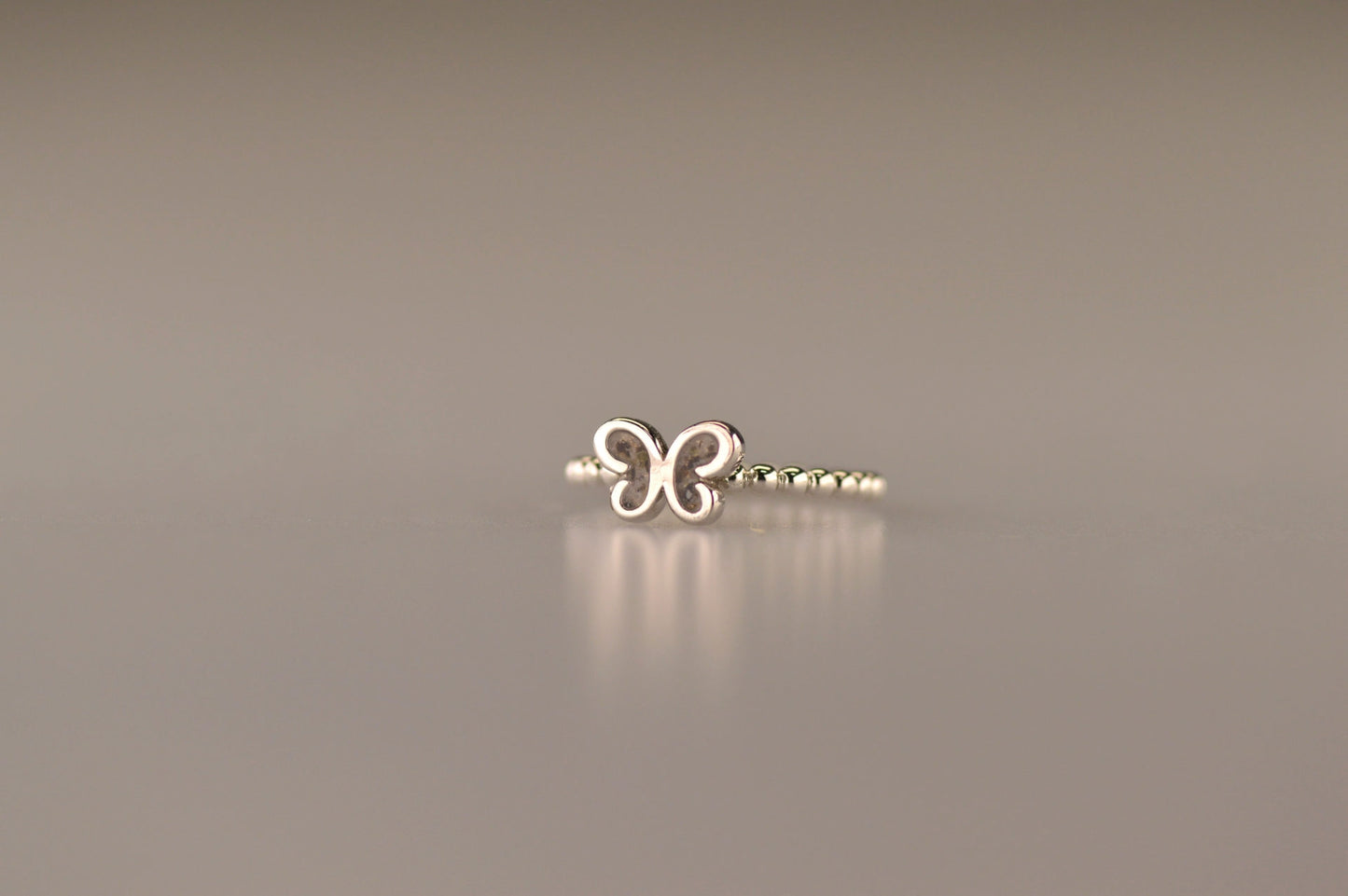 Afmeting vlinder: 8x6 mm, Ringband: 2 mm. Bolletjes ring als gedenksieraad met een vlinder er boven op , waar zichtbaar as of haar in verwerkt wordt. Alle
