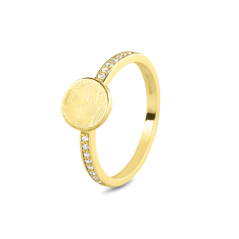 Ring 2 mm breed voorzien van een vingerafdruk/gravure, de ringband is in de bovenste helft afgewerkt met zirkonia's. Het is een tijdloos gedenksieraad en is te bestellen in zilver, 14 en 18 KT geelgoud, roségoud en witgoud.