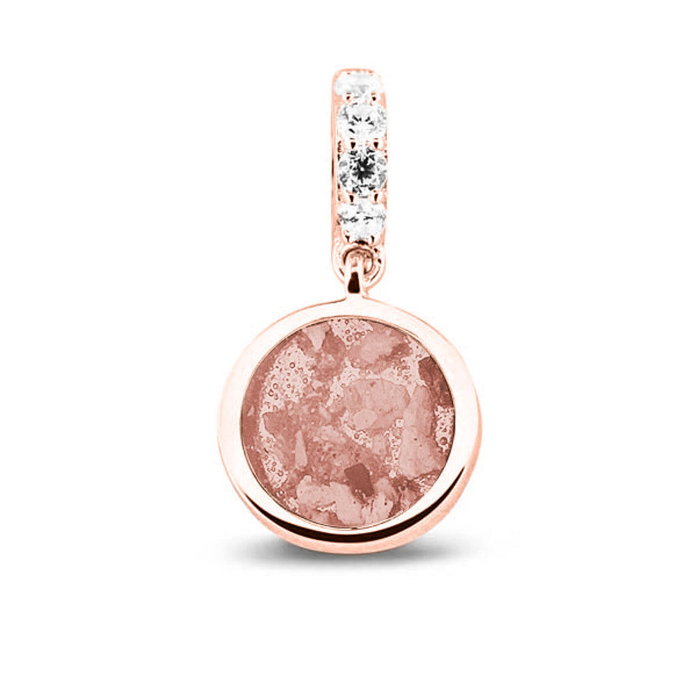 Asbedel rond subtiel design , het hangoog aan de buitenrand afgewerkt met zirkonia's, die aan de voorzijde zichtbaar gevuld wordt met as of haar met een keuze in 20 kleuren. Blush