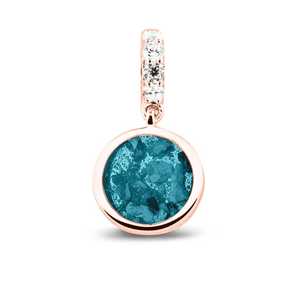 Asbedel rond subtiel design , het hangoog aan de buitenrand afgewerkt met zirkonia's, die aan de voorzijde zichtbaar gevuld wordt met as of haar met een keuze in 20 kleuren. Turquoise