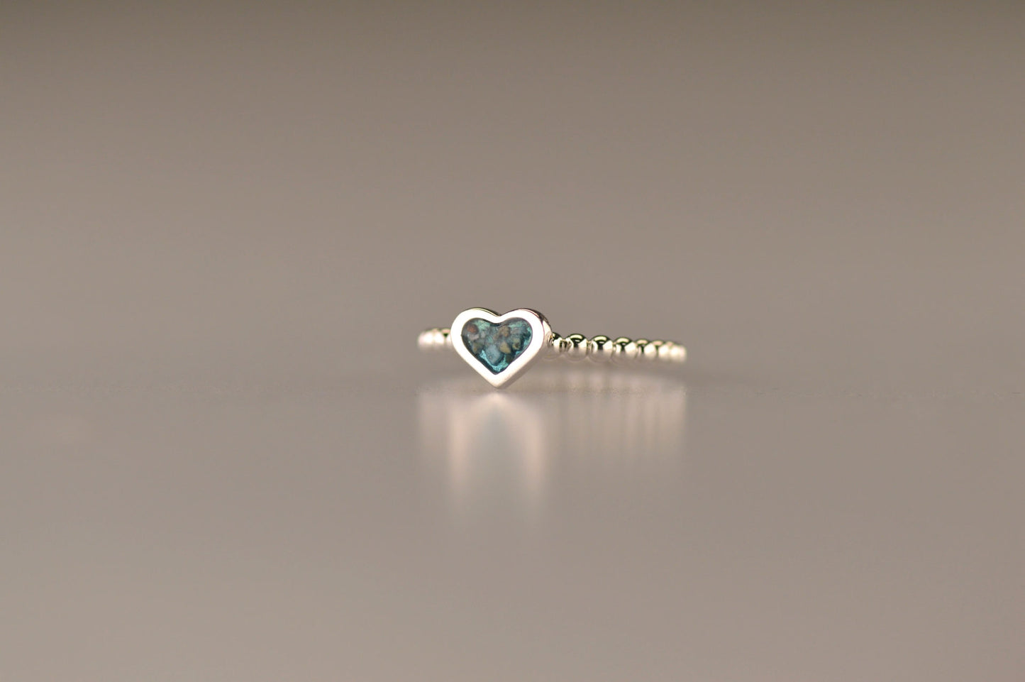 Bolletjes ring met een hartje er boven op , waar zichtbaar as of haar  in verwerkt wordt.De asring is leverbaar in zilver en in 14 en 18 KT geelgoud/witgoud en roségoud.alle
