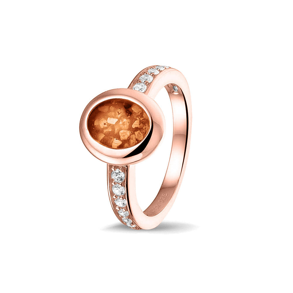 Gedenksieraad, ring 3 mm waar aan de ovale bovenzijde zichtbaar as of haar verwerkt wordt. In de bovenste helft van de ringband zijn zirkonia's of diamanten naar keuze gezet. Orange