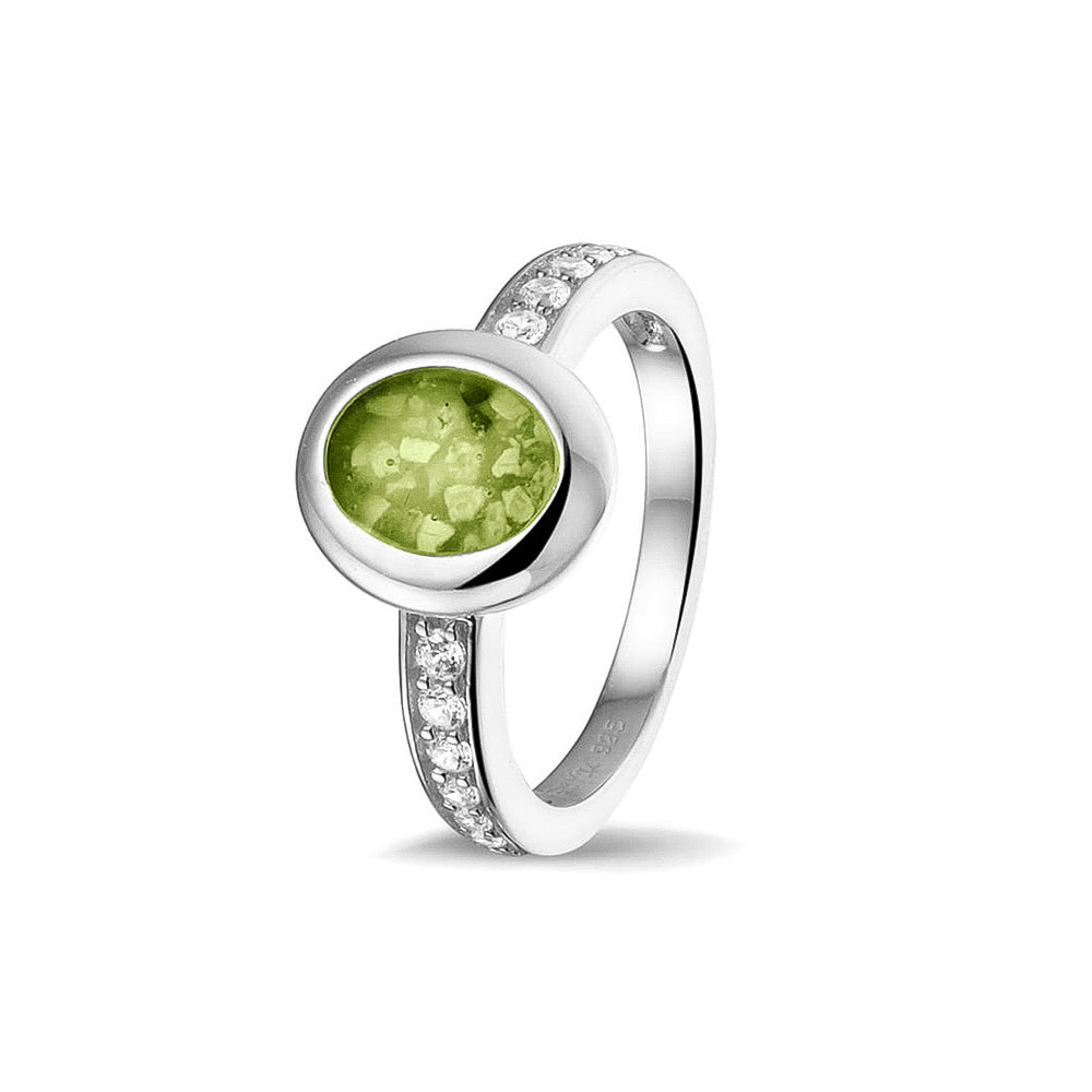 Gedenksieraad, ring 3 mm waar aan de ovale bovenzijde zichtbaar as of haar verwerkt wordt. In de bovenste helft van de ringband zijn zirkonia's of diamanten naar keuze gezet. Green