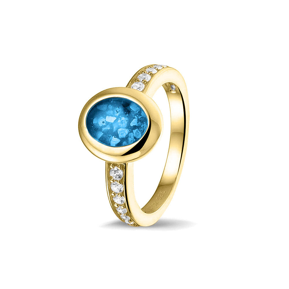 Gedenksieraad, ring 3 mm waar aan de ovale bovenzijde zichtbaar as of haar verwerkt wordt. In de bovenste helft van de ringband zijn zirkonia's of diamanten naar keuze gezet. Marine
