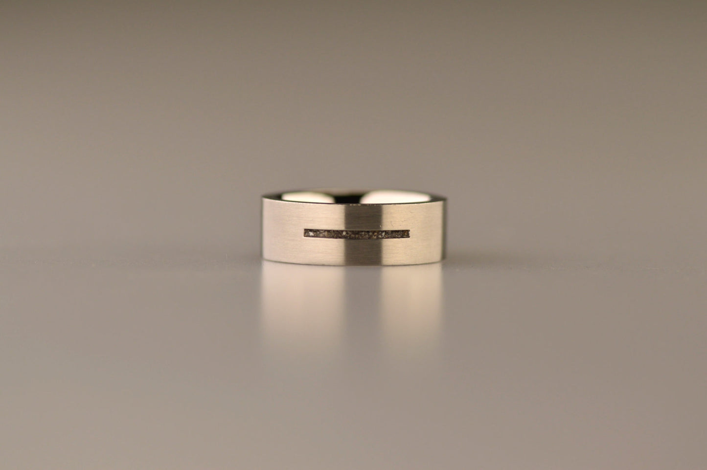 Ring als gedenksieraad 7 mm breed met één langwerpige streep waar as of haar  in verwerkt wordt.De asring is leverbaar in edelstaal, zilver en in 14 en 18 KT geelgoud/witgoud en roségoud. Alle