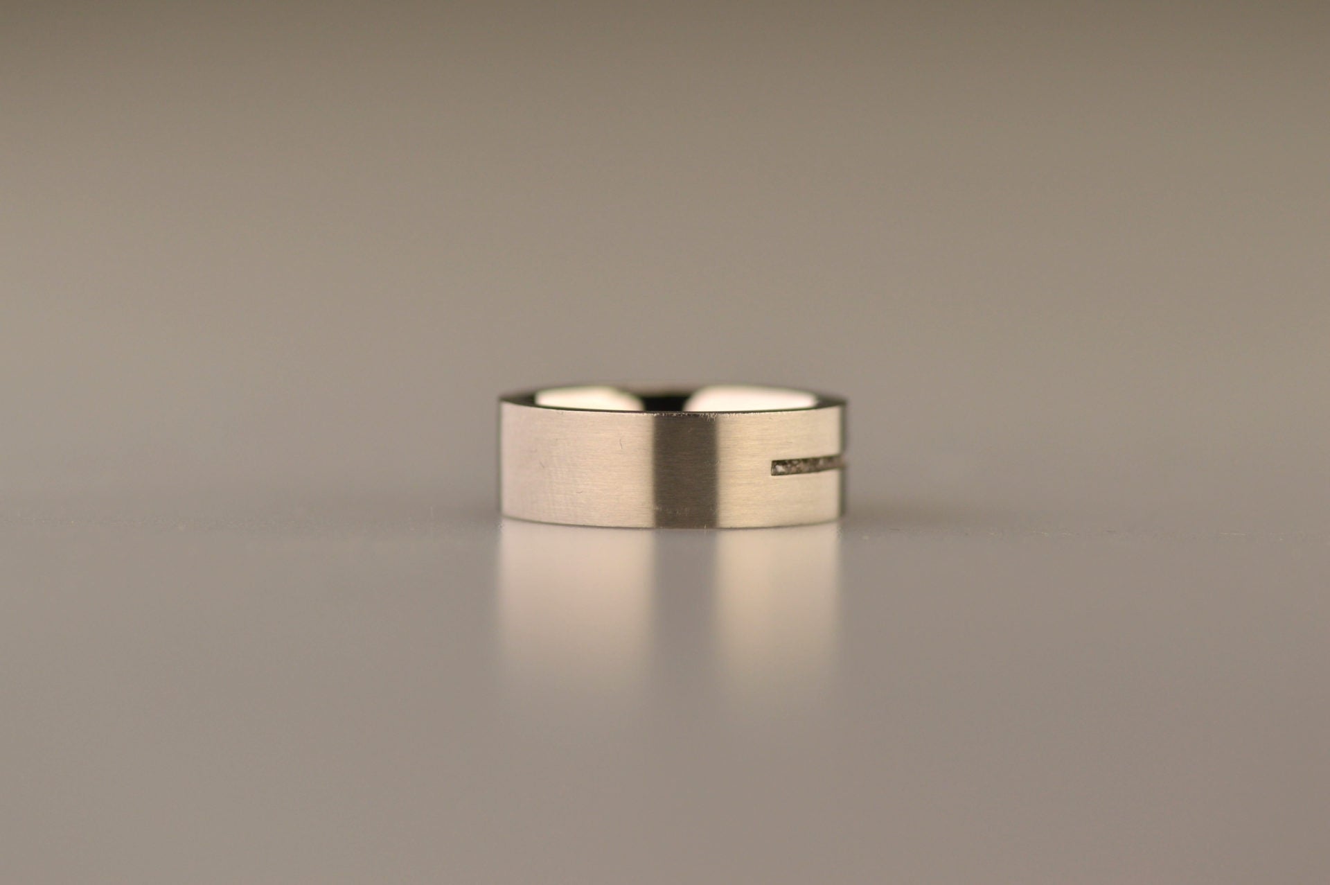Ring als gedenksieraad 7 mm breed met één langwerpige streep waar as of haar  in verwerkt wordt.De asring is leverbaar in edelstaal, zilver en in 14 en 18 KT geelgoud/witgoud en roségoud. Alle